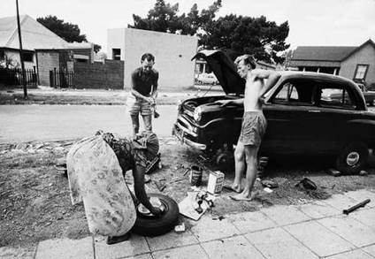 Afternoon tea being served to two men repairing a car on a sidewalk in Fairview, Johannesburg